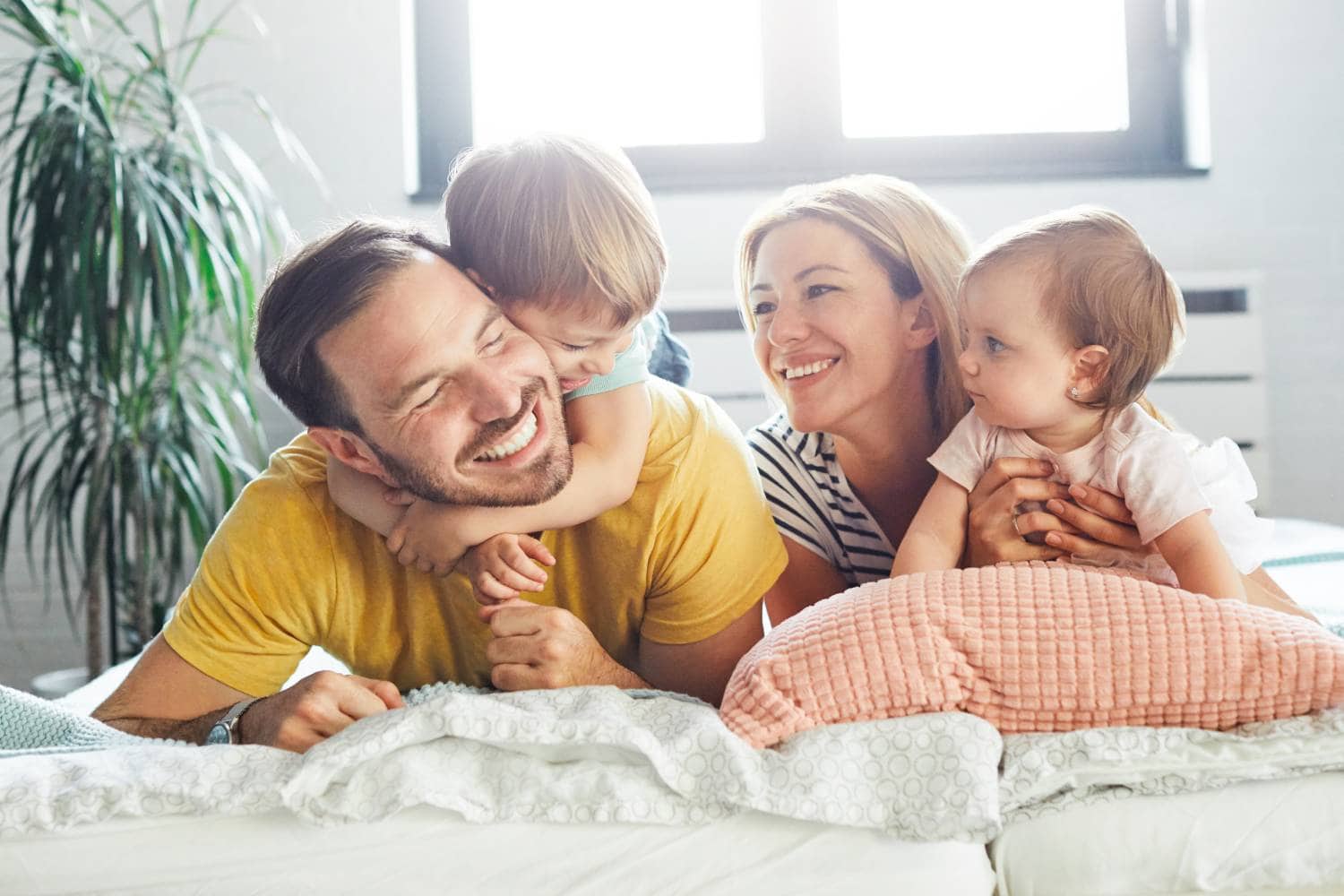 A family is laying on a bed, engaging in estate planning with their children.